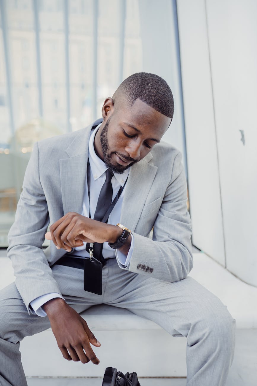 elegant office worker wearing a suit sitting and looking at his watch