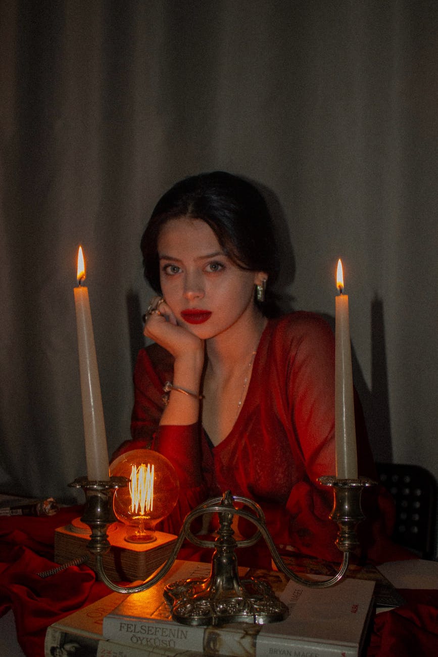 woman sitting by wax candles on table